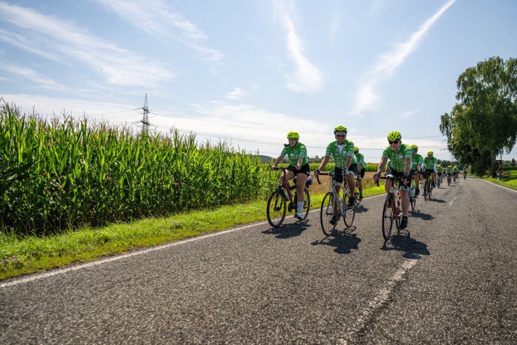Zeigt eine Gruppe von Radfahrern, die im Rahmen der Tour der Hoffnung Spendengelder für krebs- und leukämiekranke Kinder sammeln