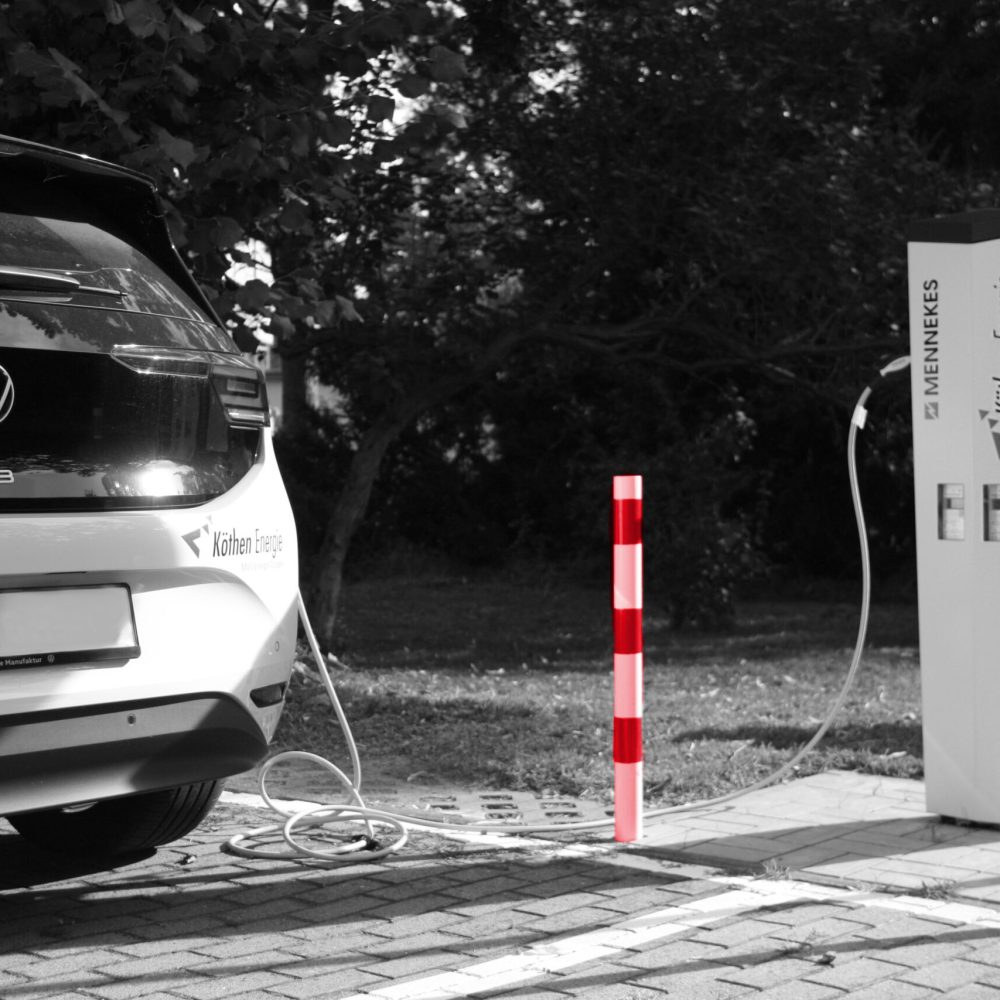 Elektroauto Volkswagen ID.3 lädt an einer Ladesäule von Köthen Energie, zwei rote Poller sichtbar.